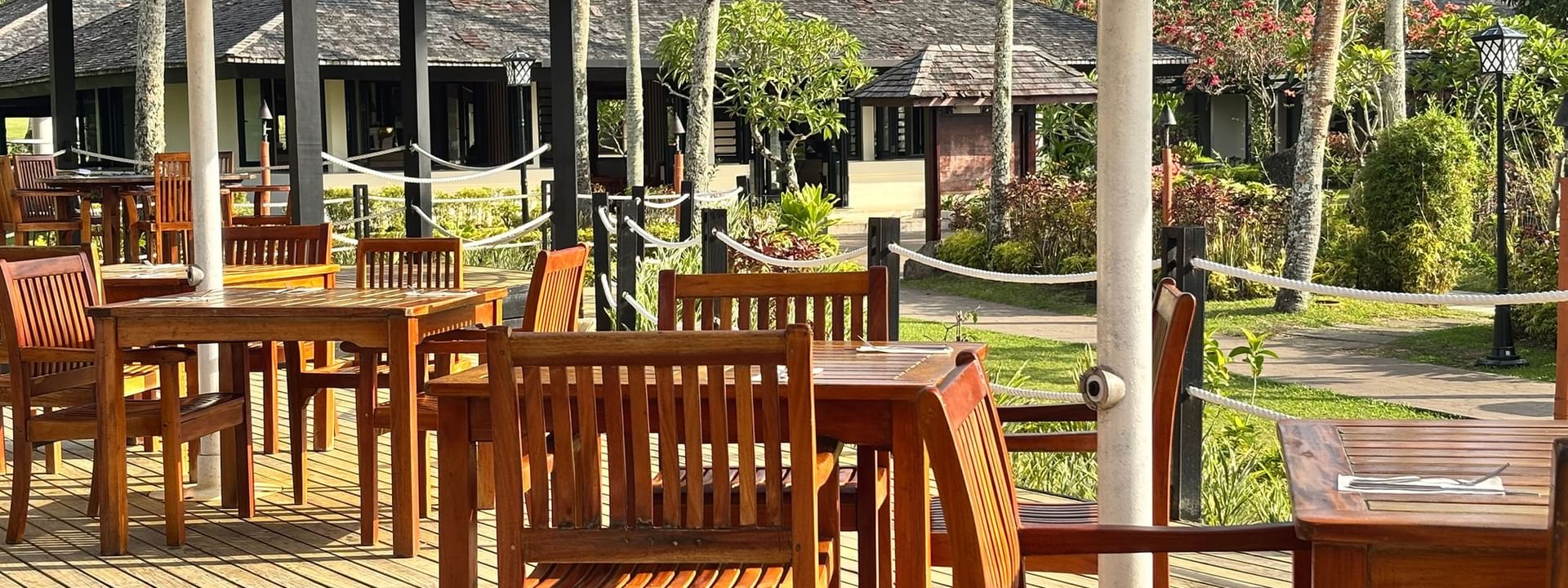 Wooden tables and chairs on a deck at Lagoon Terrace Restaurant in Efate at Warwick Le Lagon Vanuatu