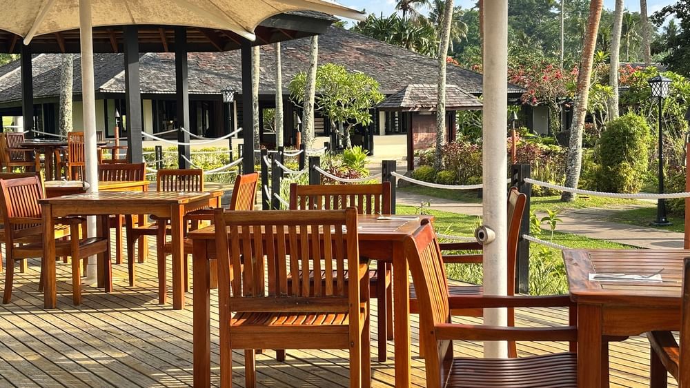 Wooden tables and chairs on a deck at Lagoon Terrace Restaurant in Efate at Warwick Le Lagon Vanuatu.