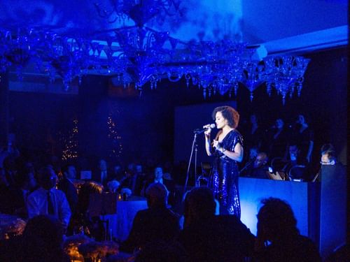 Singer performs under blue lighting in the Crystal Room at The May Fair Hotel before a seated audience