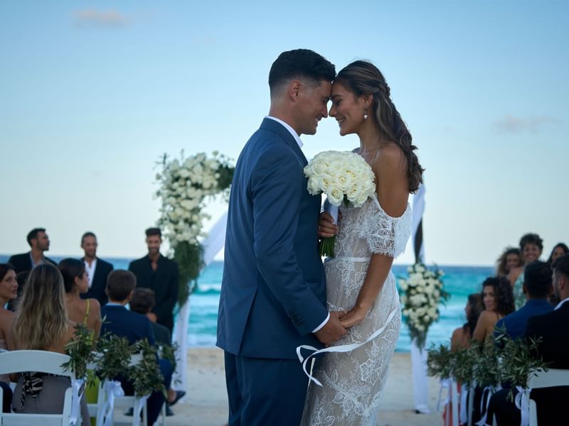 Wedded couple posing for a photo on the beach at Fiesta Americana