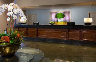 The reception desk at The Paramount Hotel Seattle with a beautiful floral arrangement and artwork