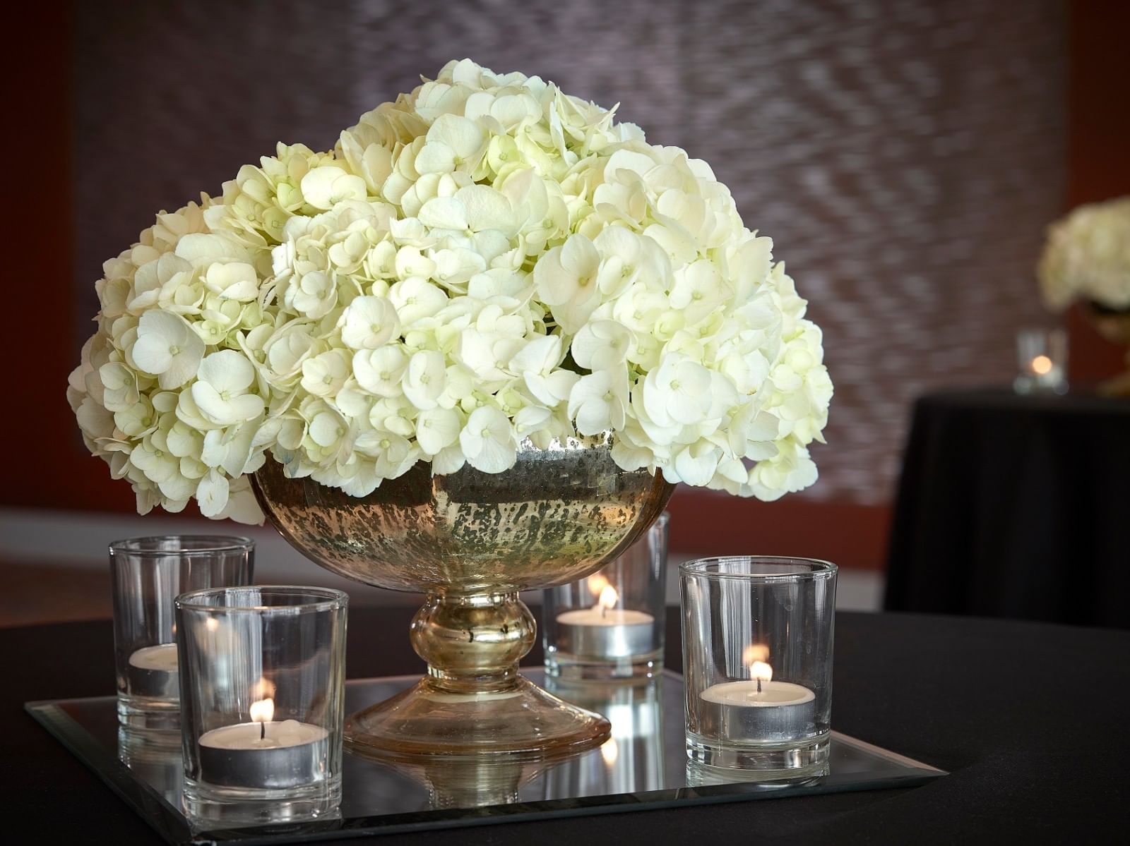Closeup of a flower vase with Candles Lit around it on a table