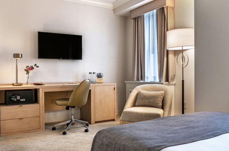 Work desk under hanging TV with bed near window in Standard Room at Warwick Allerton Chicago