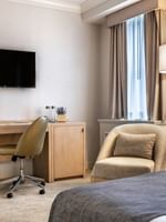 Work desk under hanging TV with bed near window in Standard Room at Warwick Allerton Chicago