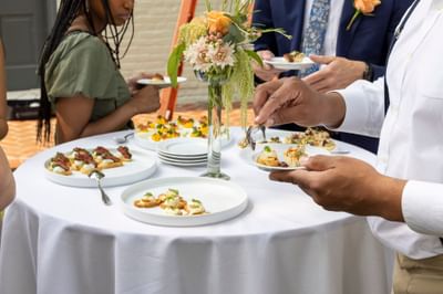 Guests selecting gourmet appetizers from white plates arranged around a floral centerpiece at The Ashbrook Hotel