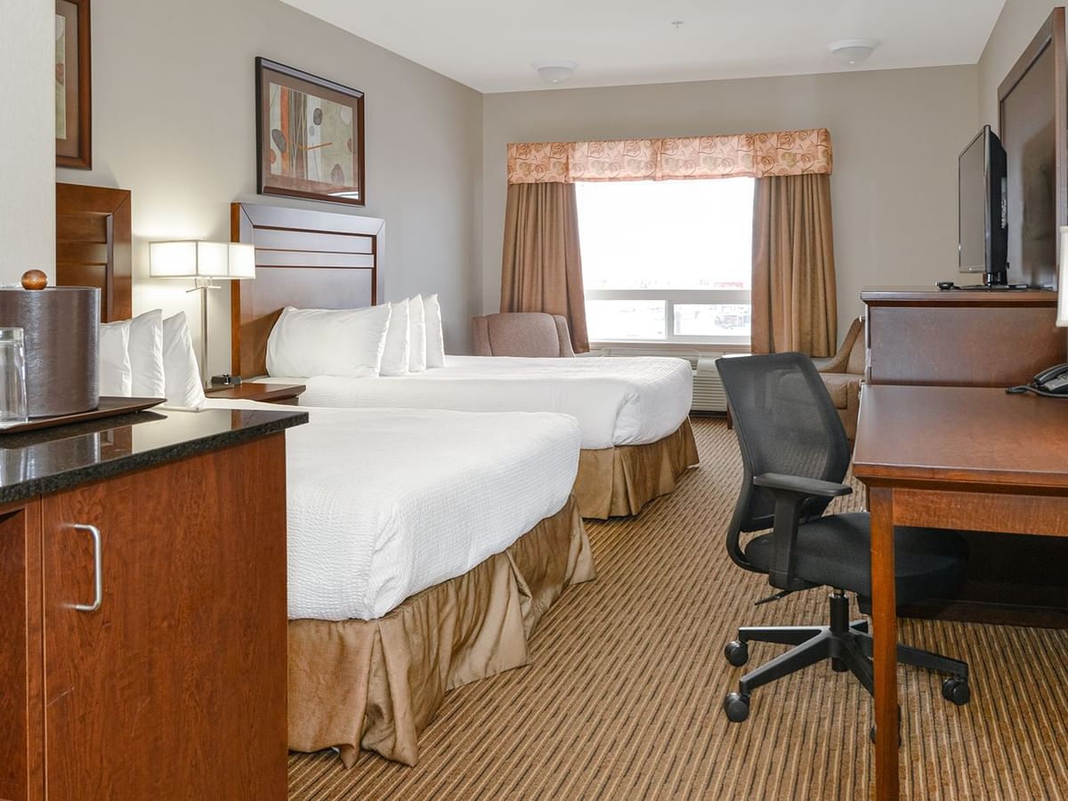 Hotel room with two queen beds, microwave, coffee machine, TV, work desk and chair