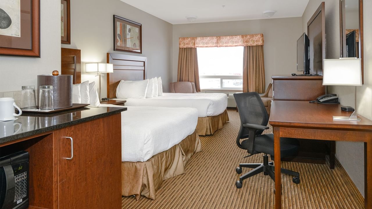 Hotel room with two queen beds, microwave, coffee machine, TV, work desk and chair