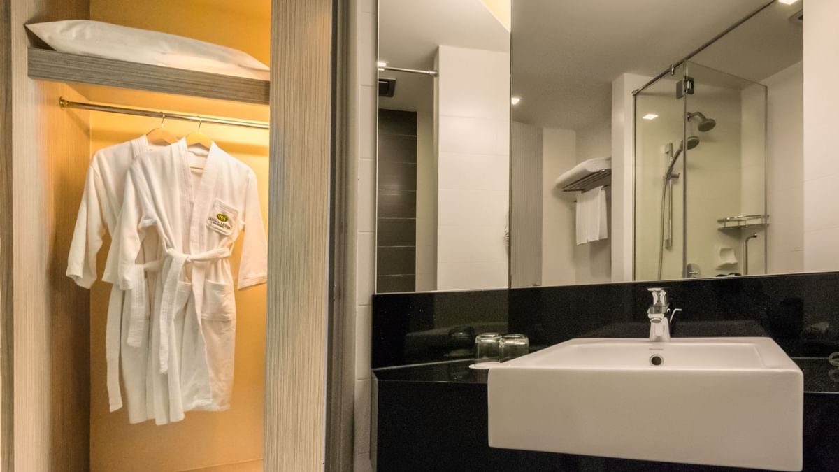 Spacious open closet with a bathrobe by a modern bathroom sink in a Deluxe King Room at Sunway Hotel Seberang Jaya