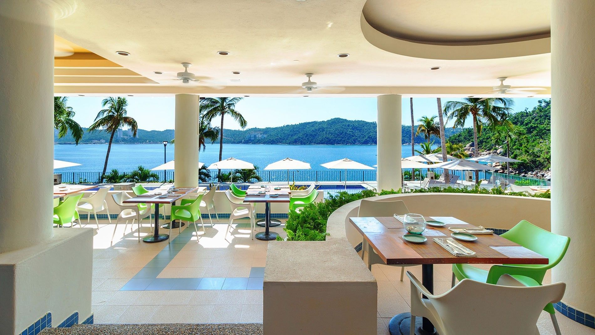 Wide view of Pool Bar dining area facing the calm blue ocean at Camino Real Acapulco Diamante