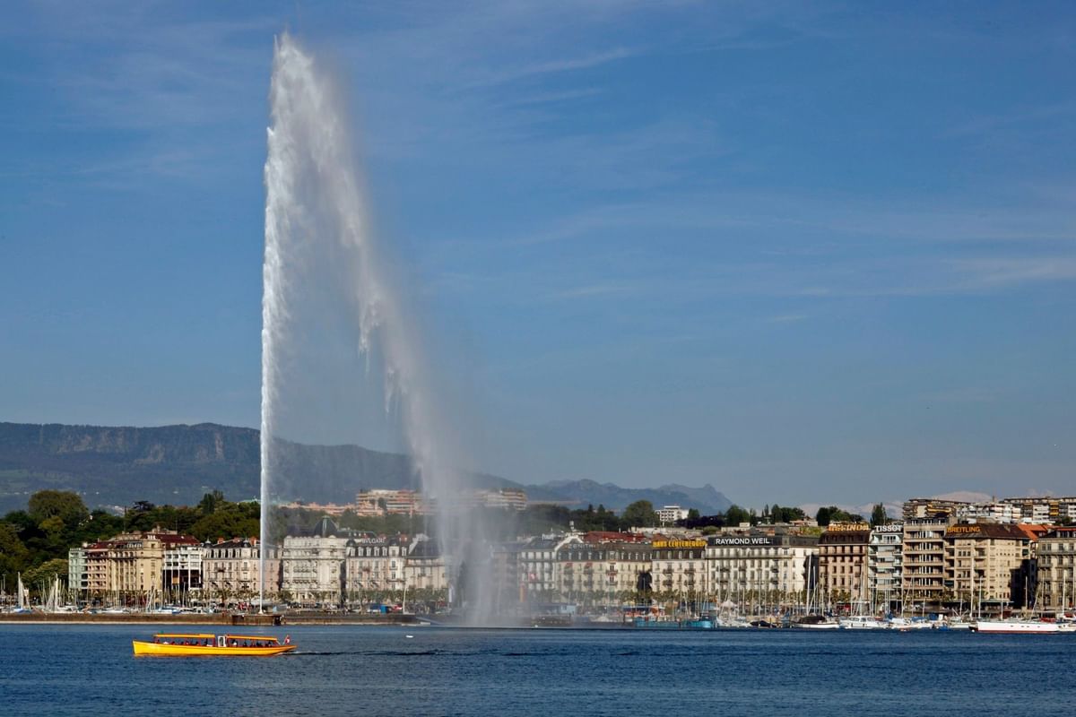 Jet d'Eau fountain with Giant water fountain by a blue lake and a yellow boat Warwick Geneva