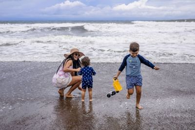 Mother and two small children playing with sand toys in the surf near the ocean at Best Western Jaco Beach
