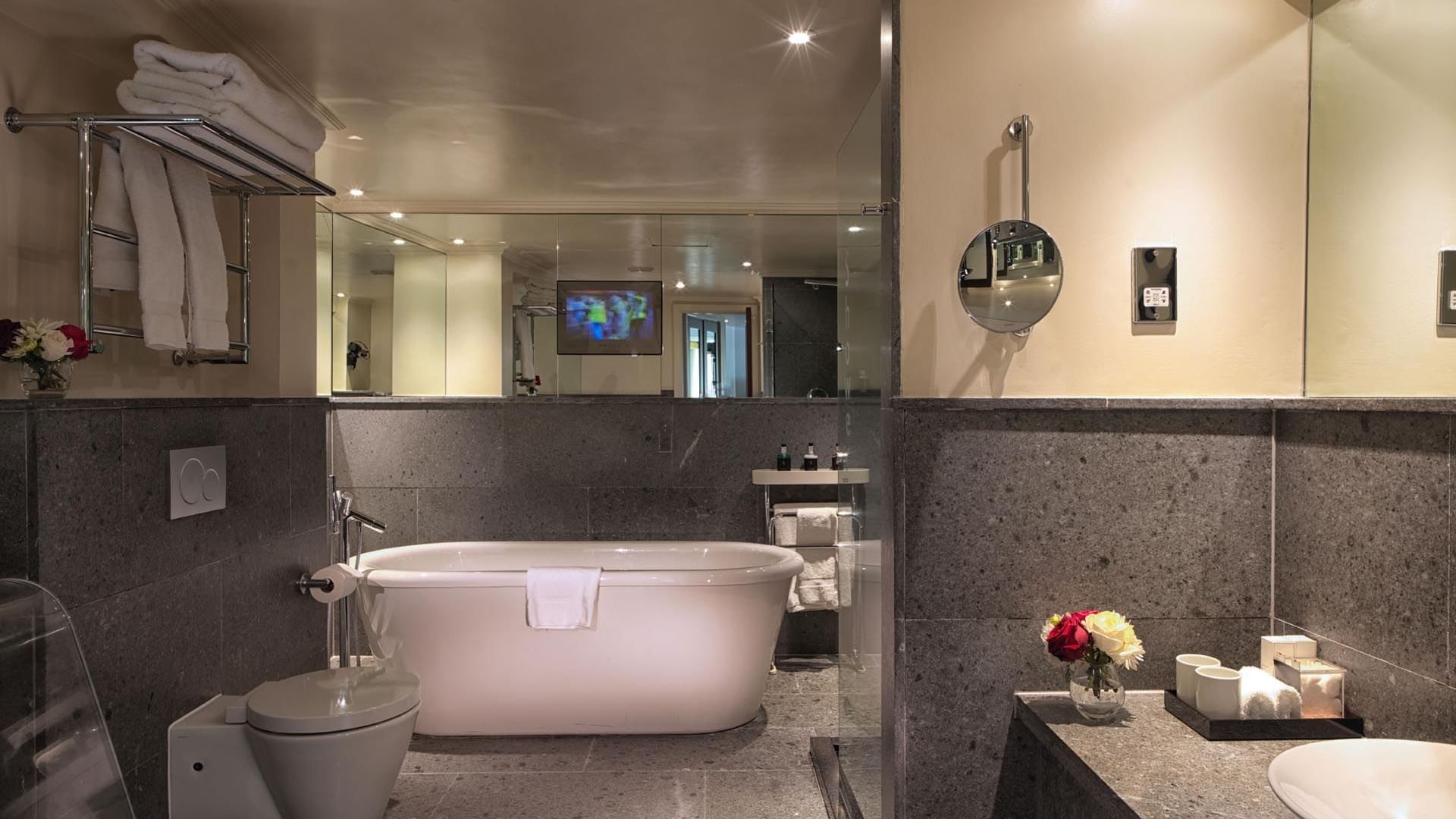 Elegant Studio Suite bathroom at The May Fair Hotel with vessel sinks on a black countertop, toilet, and bathtub