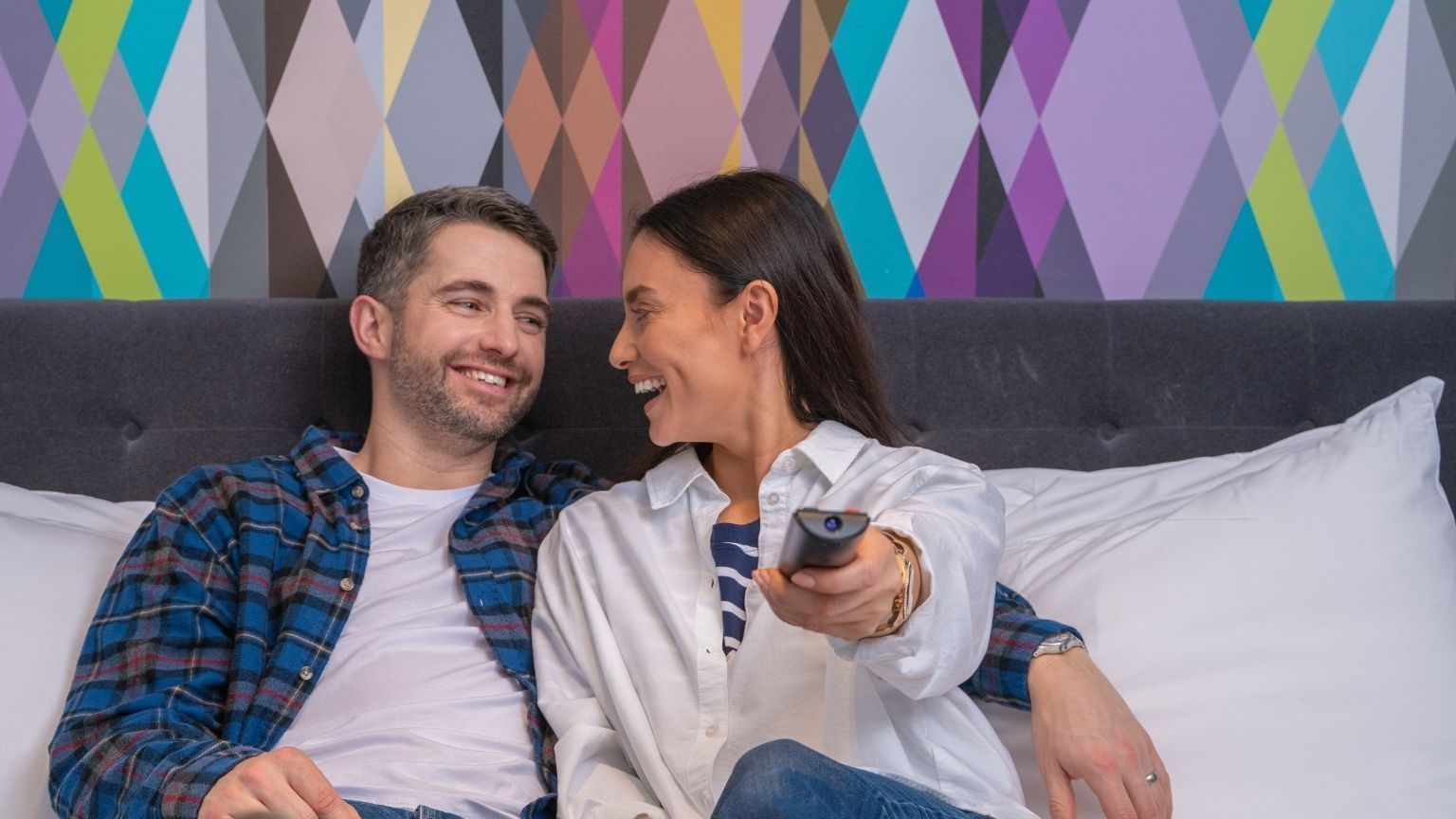 A couple watching TV while in bed at Village Hotel Liverpool