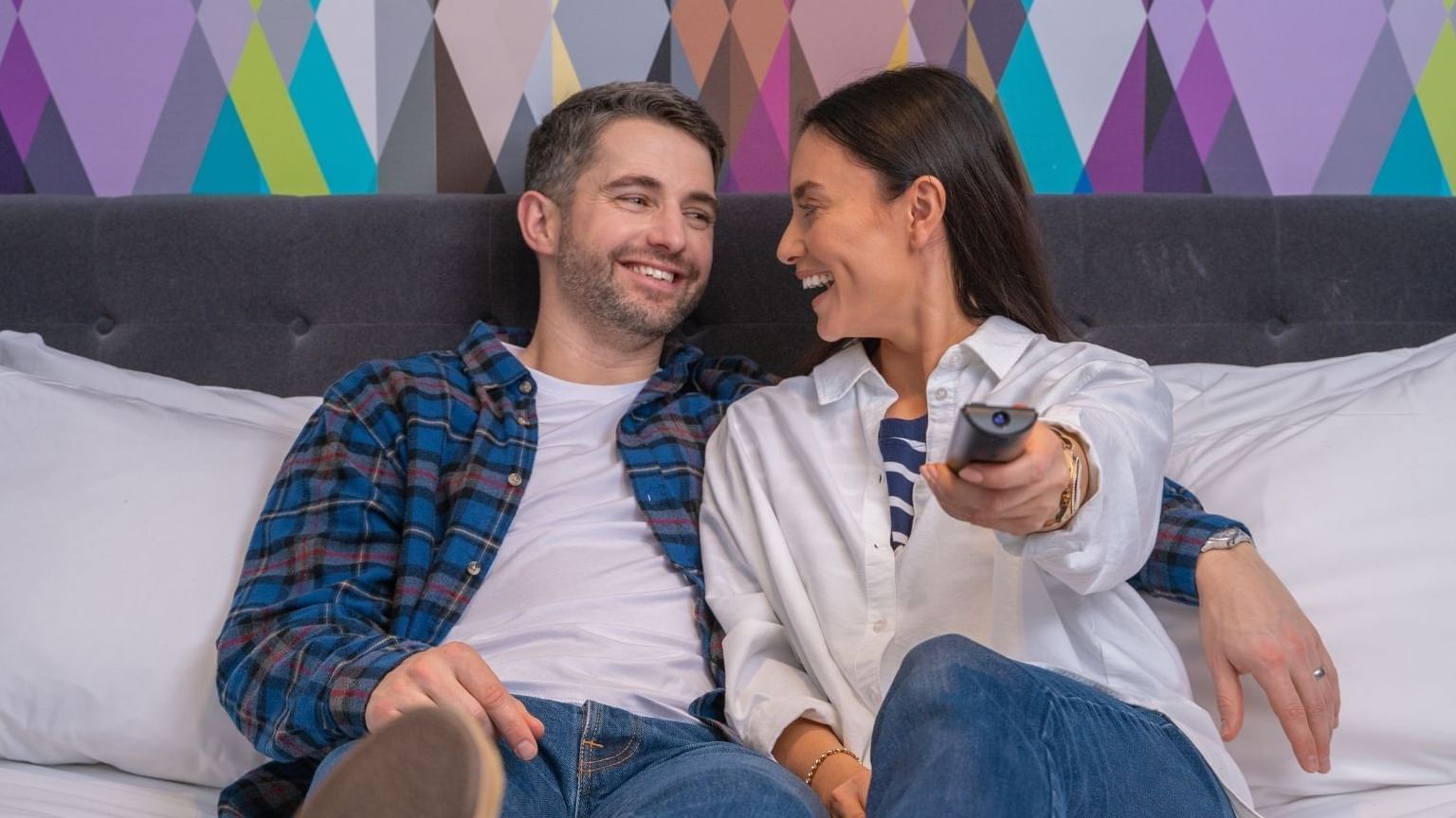 A couple enjoying TV in a bedroom at Village Hotel Solihull