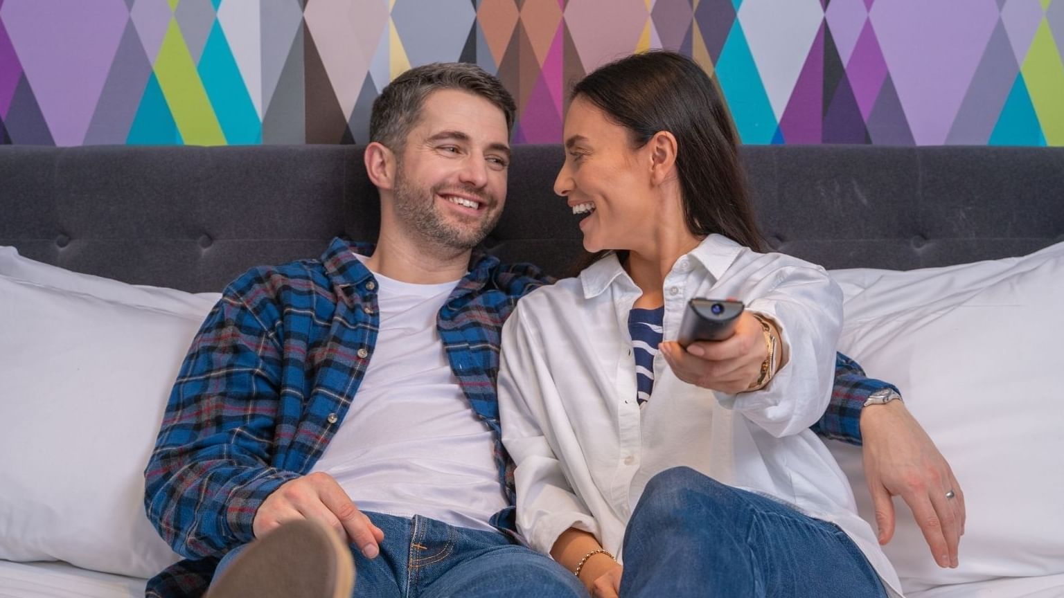 A couple watching TV while in bed at Village Hotel Leeds North
