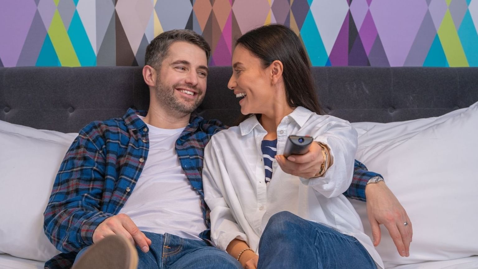 A couple watching TV from a bed at Village Hotel Birmingham