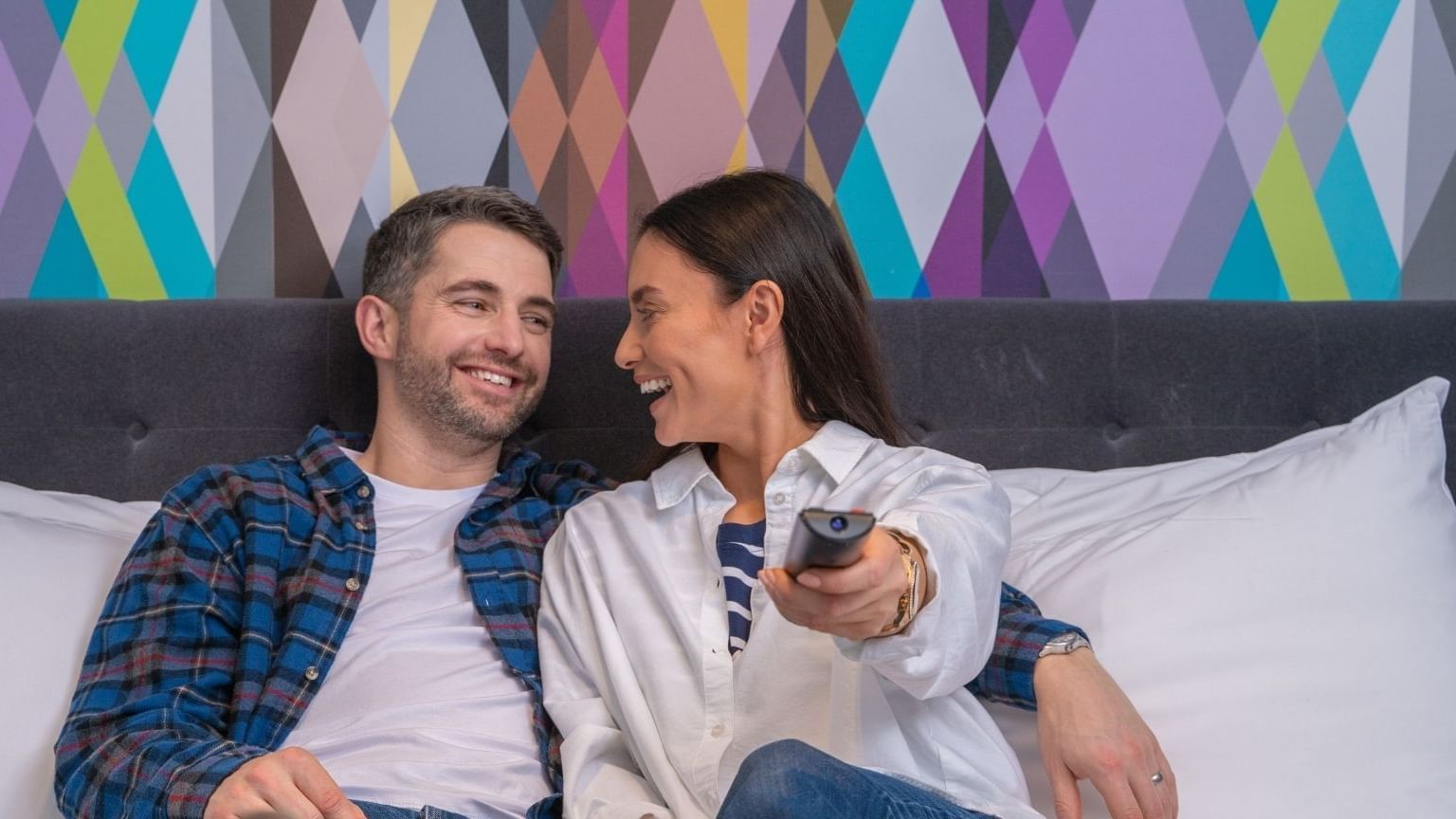 A couple enjoying TV in a bedroom at Village Hotel Nottingham