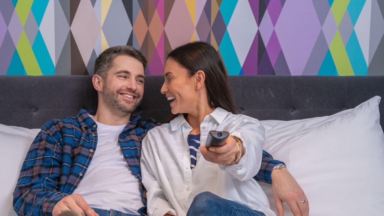 A couple enjoying TV in a bedroom at Village Hotel Newcastle