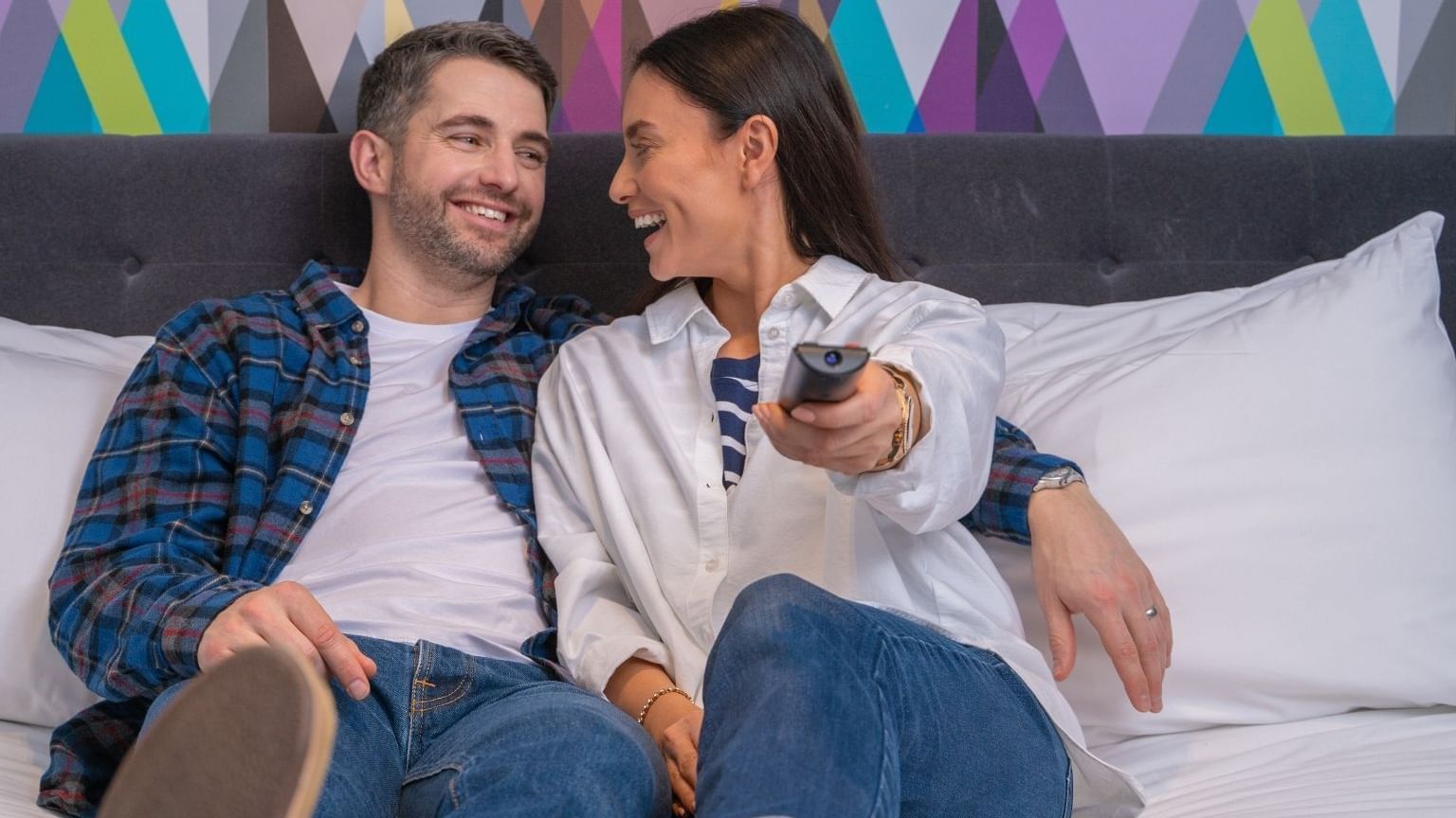 A couple watching TV while in bed at Village Hotel Cheadle