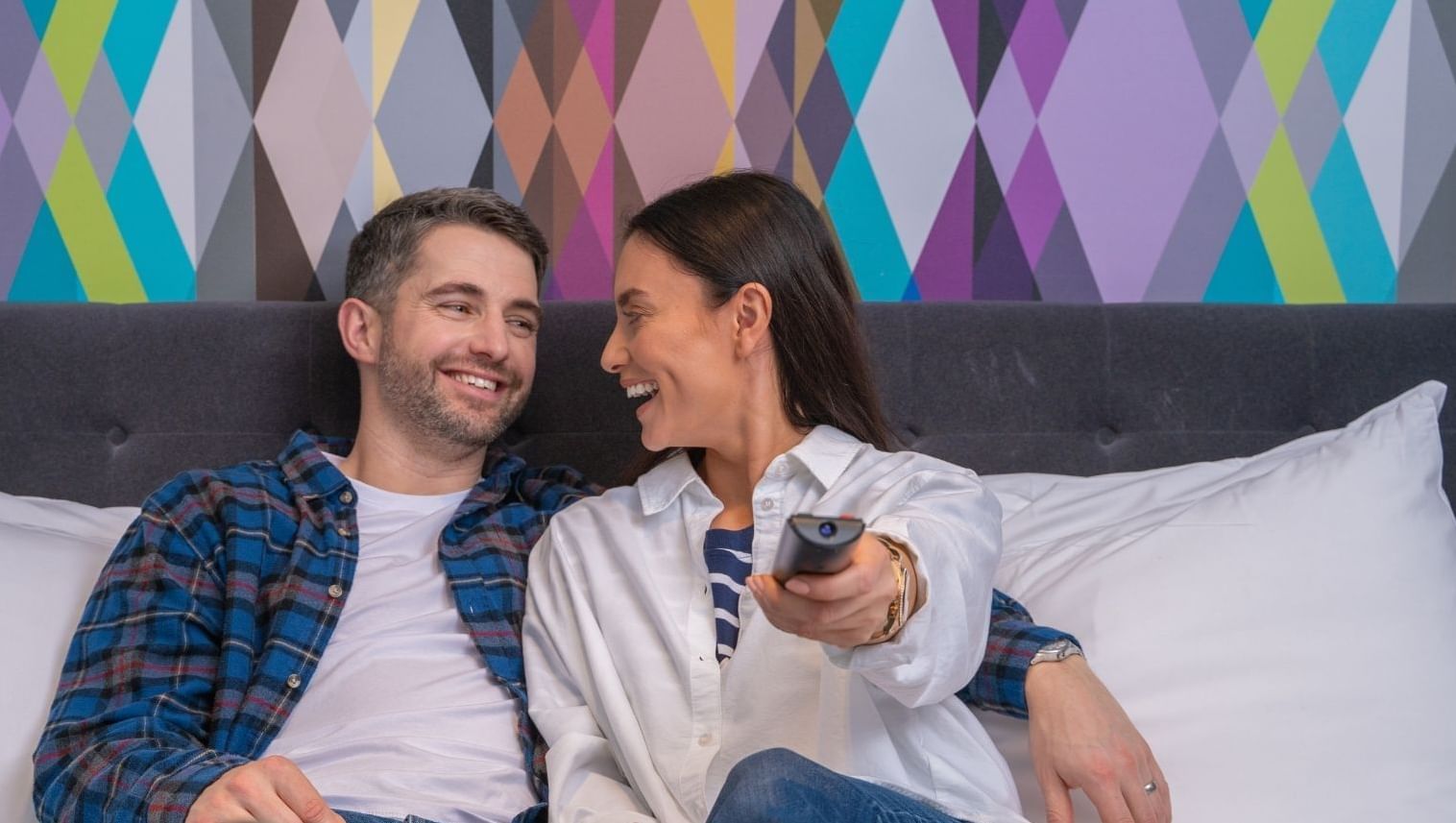 A couple enjoying TV in a bedroom at Village Hotel Maidstone