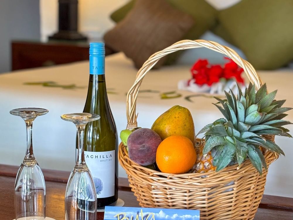 Bottle of wine and basket of fruits on table in Studio Villa at The Naviti Resort in Korolevu.