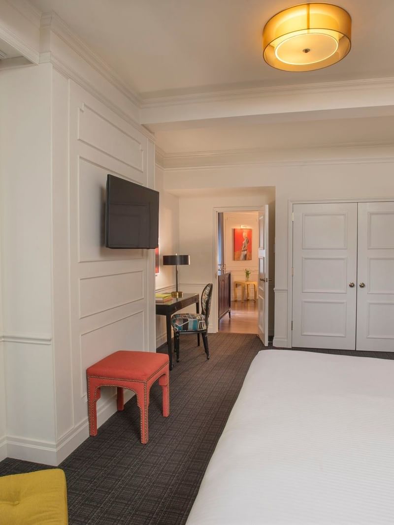 Modern Art Suite featuring bed with wall-mounted TV & red ottoman and yellow armchair at Warwick New York