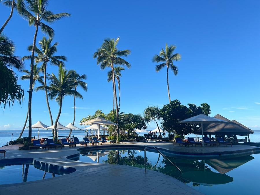 Oceanfront pool area with sun loungers and umbrellas at Warwick Fiji Resort and Spa.