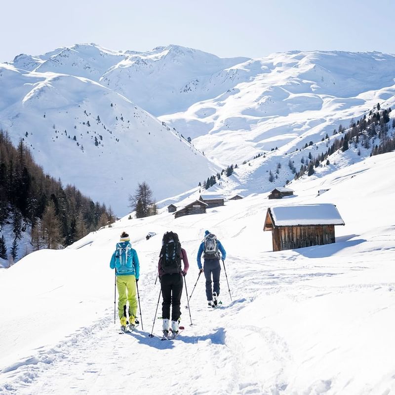 Three people skiing on a snowy hill near Falkensteiner Hotels