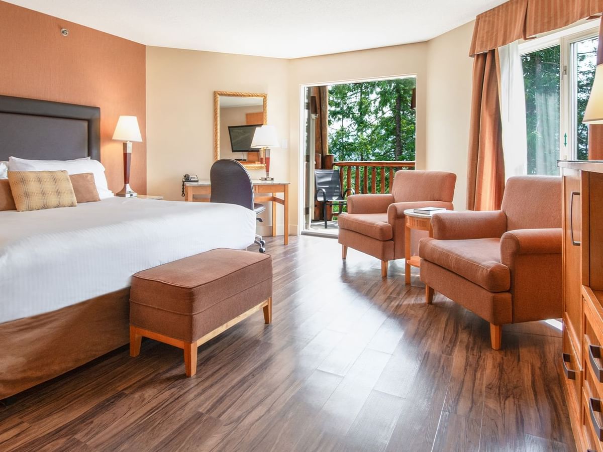 Hotel suite with king bed, arm chairs, work desk and a balcony