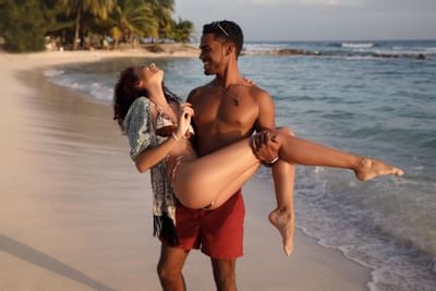 Man holding his girlfriend in his arms by the sea at Sugar Bay