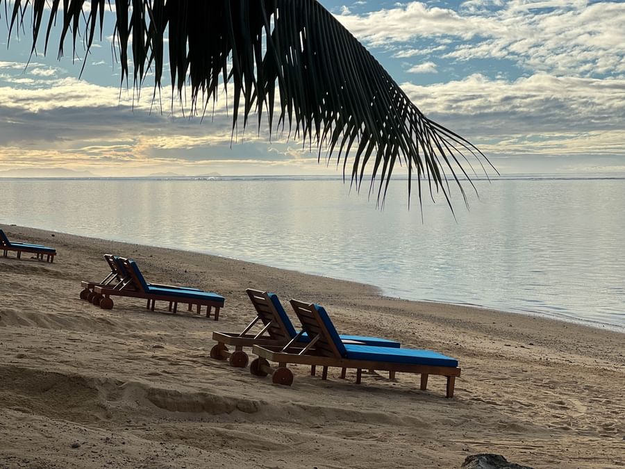 Beach chairs on the sandy shore by the ocean at Warwick Fiji Resort and Spa.