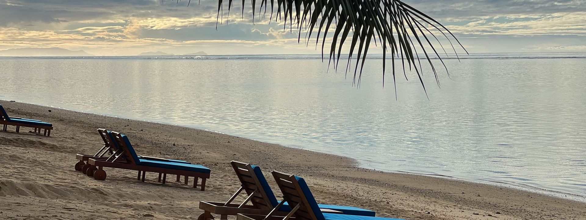 Blue beach loungers on sand beach with ocean view at Warwick Fiji Resort and Spa, Korolevu