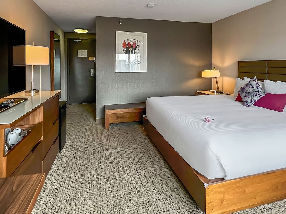 Hotel bedroom with bed, TV, and fridge