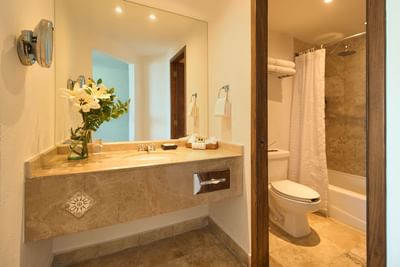 A luxury hotel suite bedroom featuring a king-size bed decorated with elegant turquoise accents.