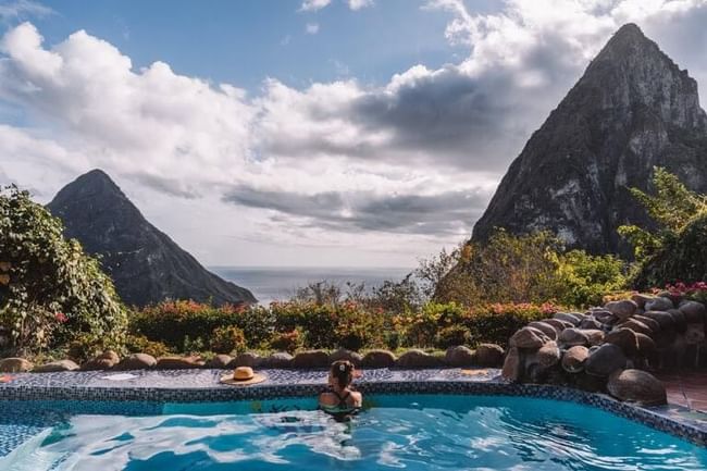 A woman in a pool overlooking mountains and the sea at Ladera Resort