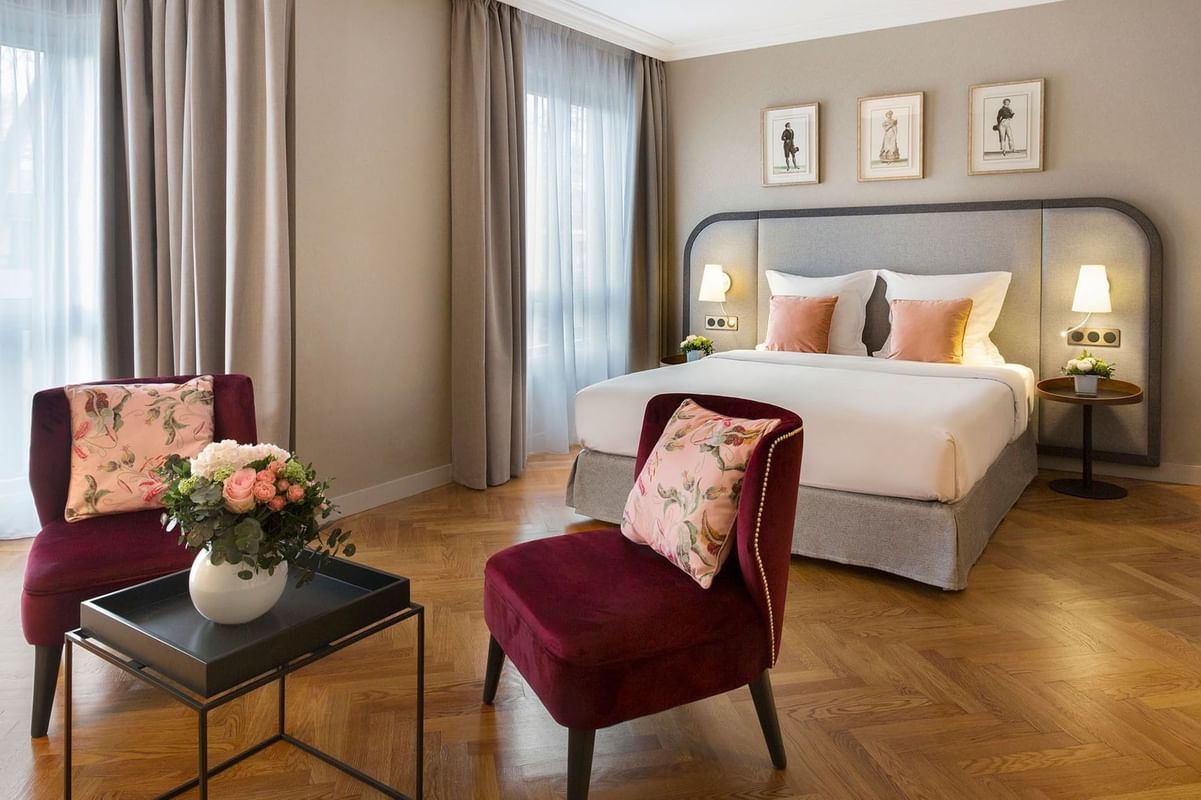 Chambre élégante avec lit double, fauteuils bordeaux, parquet en chevrons et tableaux encadrés au Warwick Reine Astrid-Lyon
