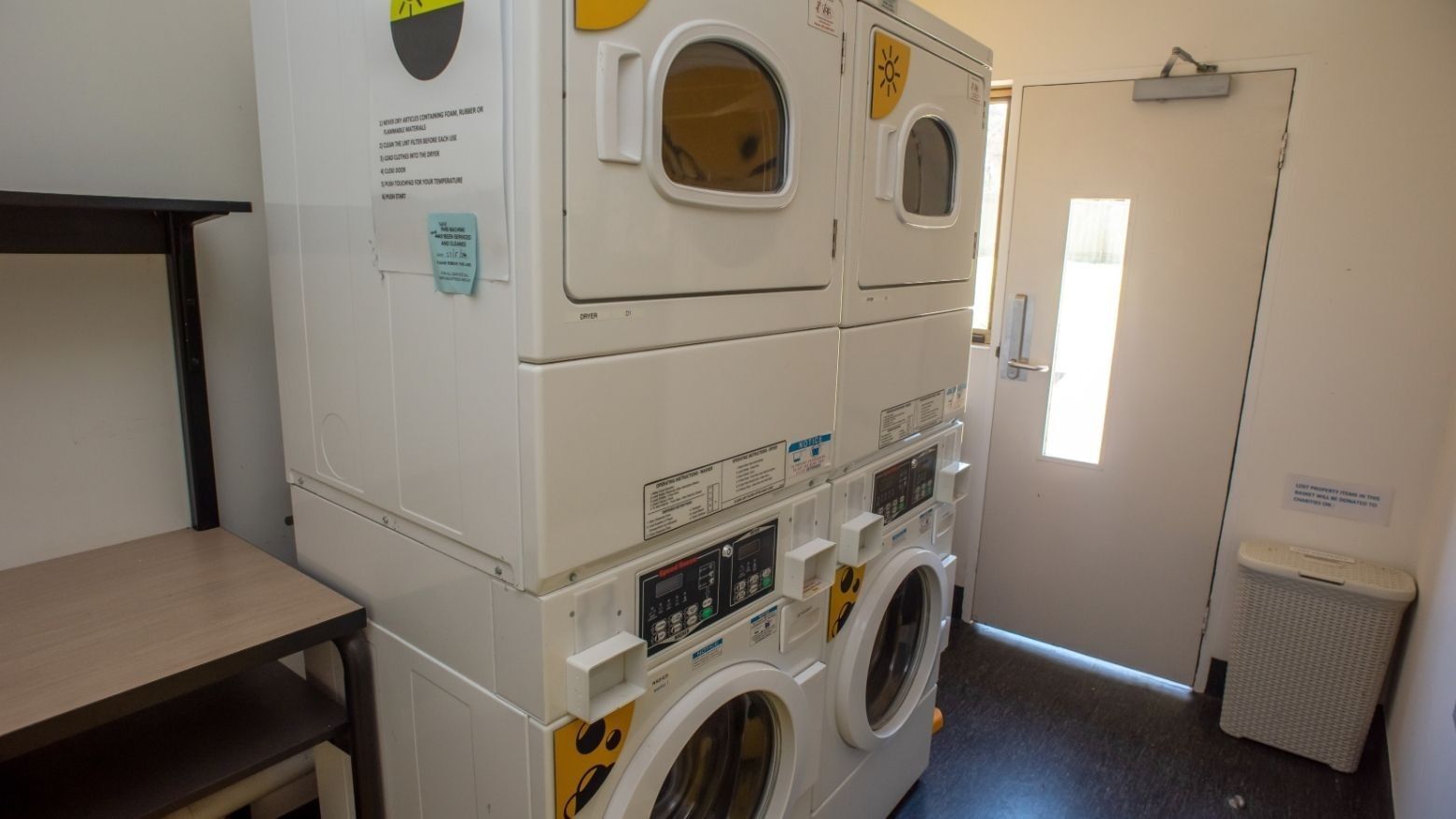 Four white stacked washers and dryers in a room at La Trobe University - Orde House.