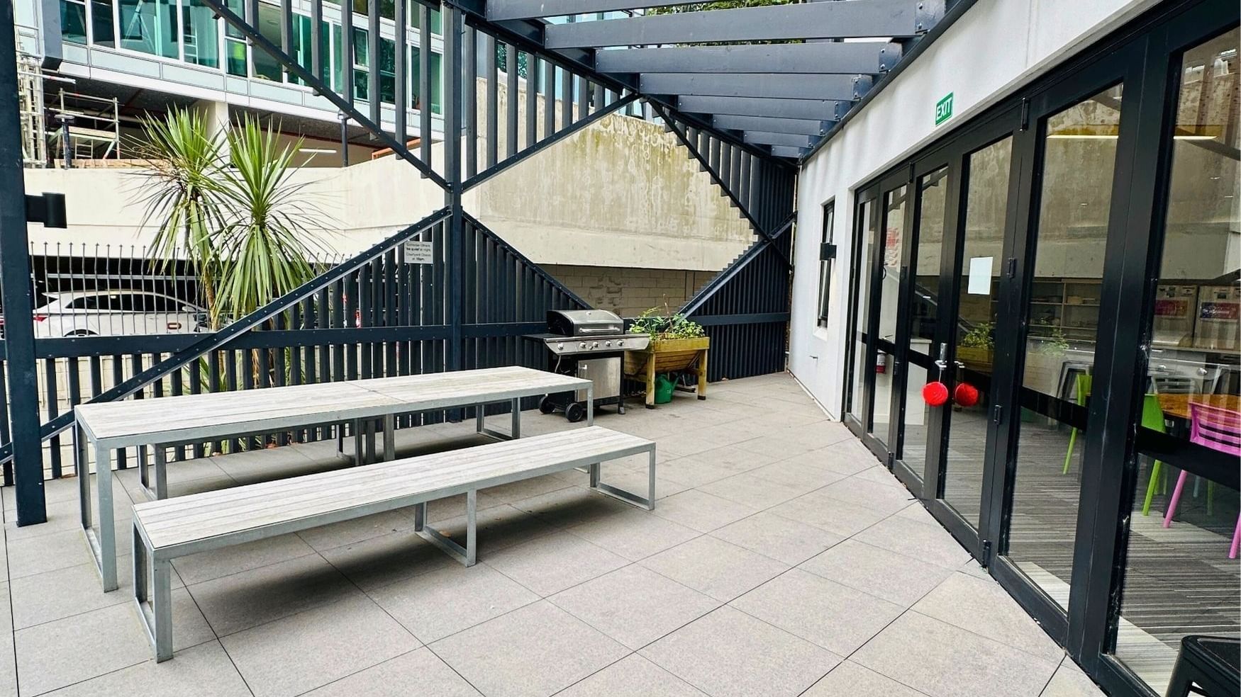 Outdoor seating area with tables and benches under a covered structure at UniLodge Auckland City.