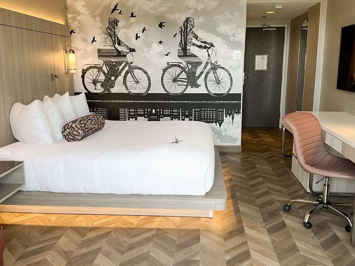 Hotel guestroom with King bed, sofas, work desk, TV, chair, and nightstand.