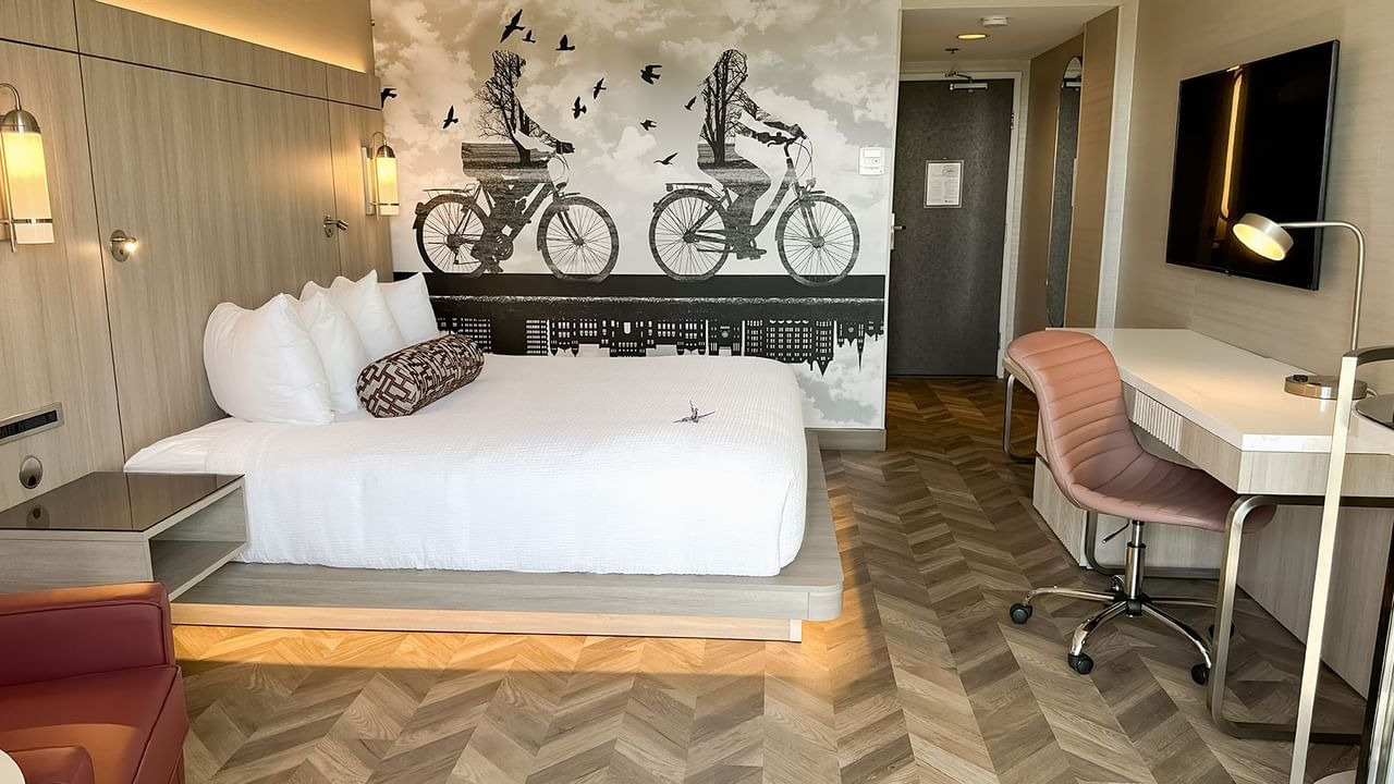 Hotel guestroom with King bed, sofas, work desk, TV, chair, and nightstand.