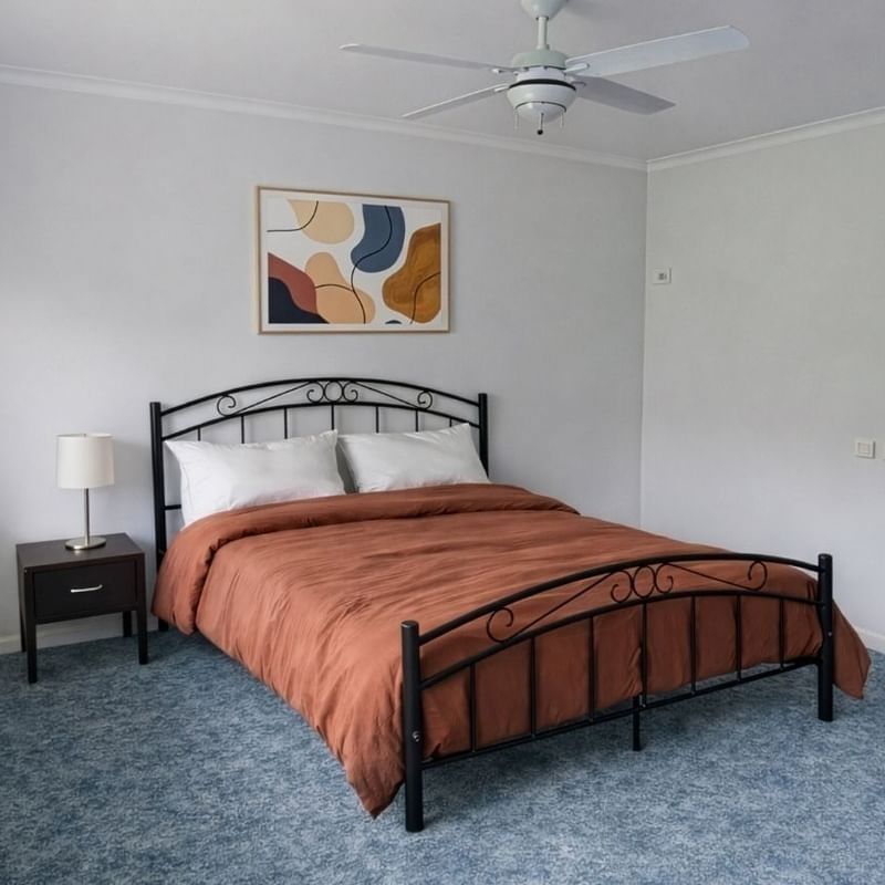 Bedroom with blue carpet, large window, bed, nightstand, and painting at UniLodge SCU Lismore - Sirius.