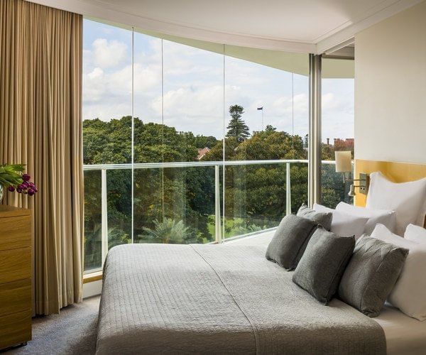 Comfy king bed with plush pillows overlooking the trees from a tall window at Pullman Quay Grand Sydney