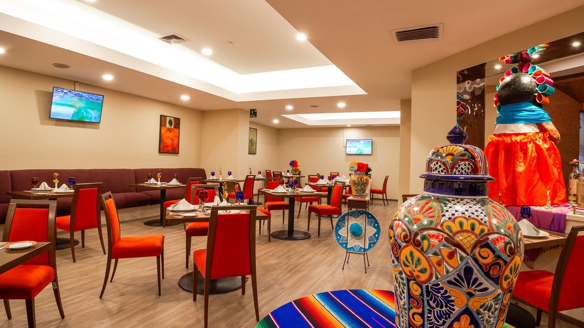 Cualli restaurant interior with Mexican-themed decor and red dining chairs at Camino Real Aeropuerto Mexico