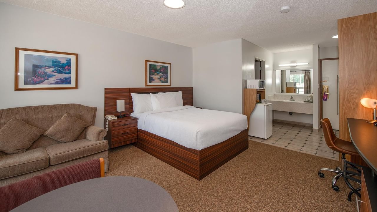 guest room with one queen bed, sofa and wood furnishings at Coast Whitecourt Hotel