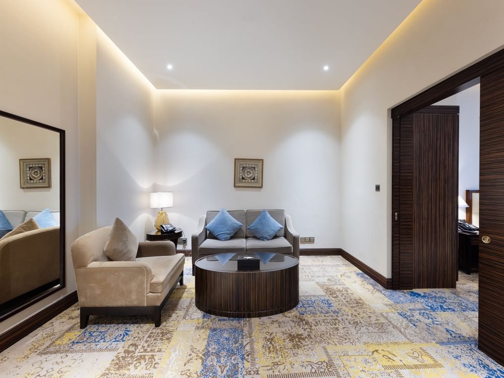 Executive Room featuring a sofa with blue pillows by a round wood table under soft light at Warwick Al Khobar