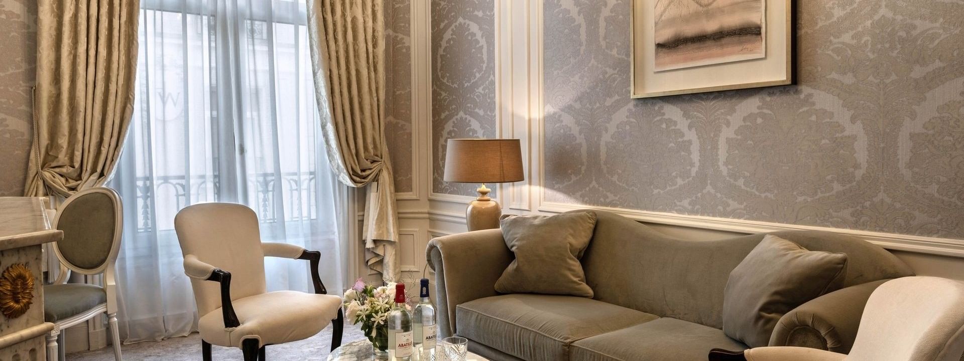 Lounge with a velvet sofa and armchairs by a marble table in Deluxe Suite Belle Époque at Hotel Westminster Paris