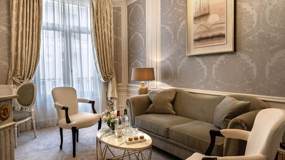 Lounge with a velvet sofa and armchairs by a marble table in Deluxe Suite Belle Époque at Hotel Westminster Paris