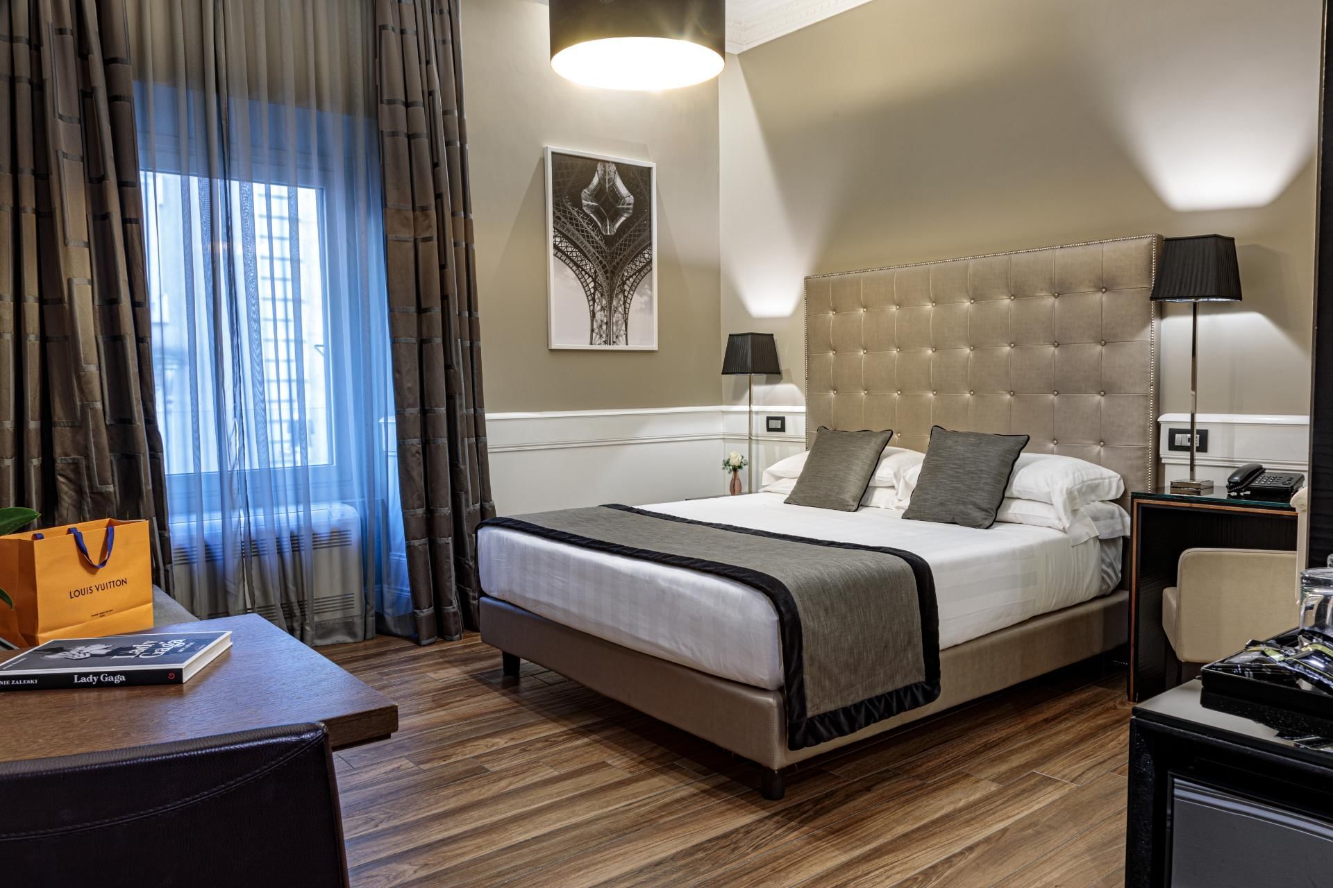 Cozy Deluxe Room with a king bed, chic decor, desk, sheer-curtained windows, and elegant lighting at The Independent Suites