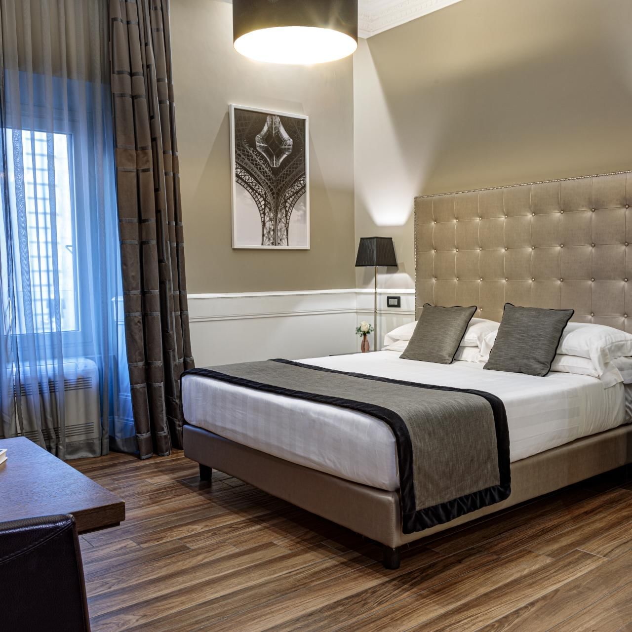 Cozy Deluxe Room with a king bed, chic decor, desk, sheer-curtained windows, and elegant lighting at The Independent Suites