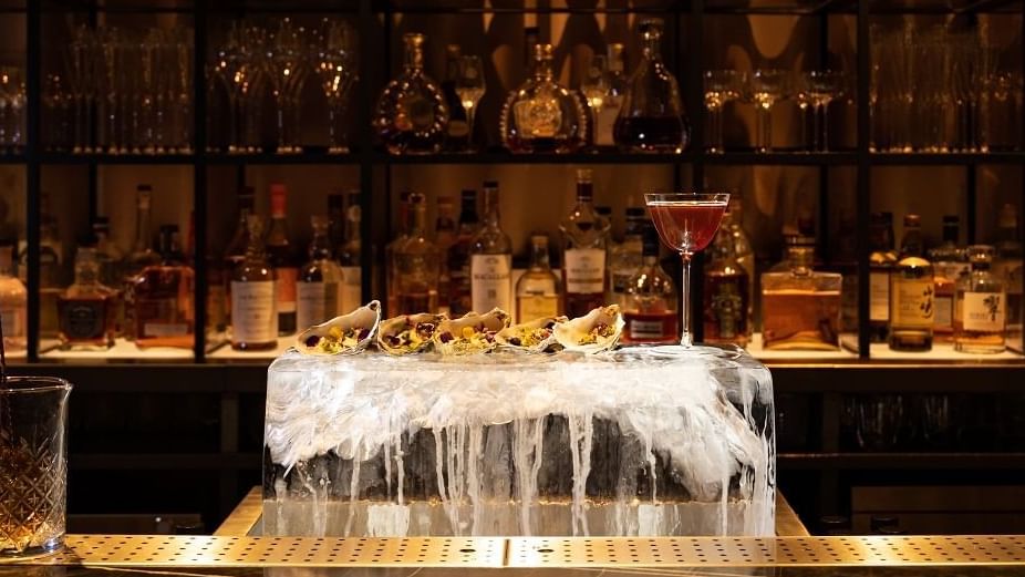 Bar with warm abience & towering ice sculpture in the middle at The Londoner Hotel